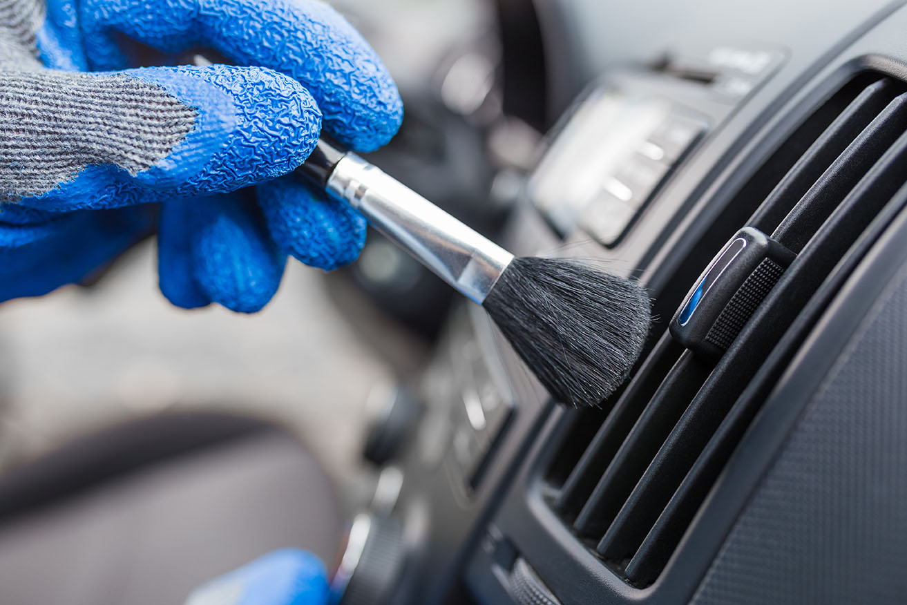 Car detailer brushing the AC vents in a car